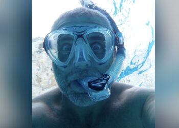 Neil Coffey snorkelling underwater on a summer holiday, wearing a blue diving mask and snorkel